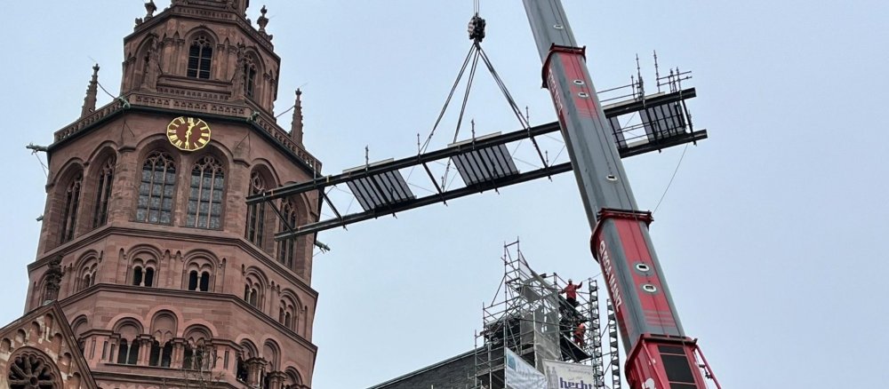 Eine Gerüstbrücke wird mit einem Kran vom Dach des Mainzer Doms abgehoben