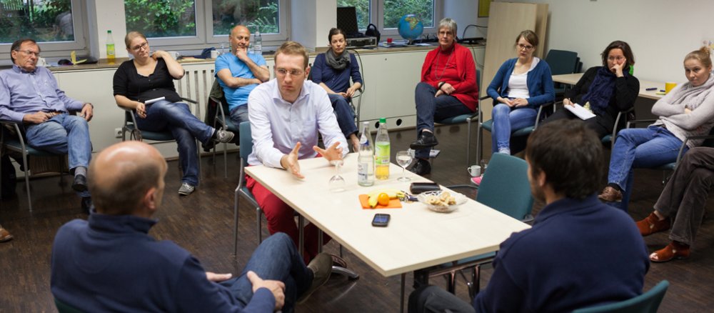In einem Seminarraum diskutieren mehrere Menschen gemeinsam.