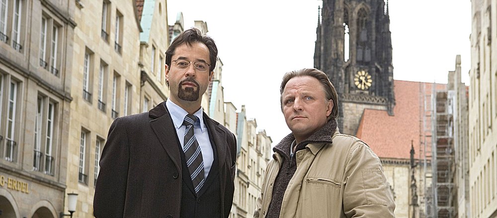 Die Ermittler aus dem Münster-"Tatort": Rechtsmediziner Karl-Friedrich Boerne (l., gespielt von Jan-Josef Liefers) und Kriminalhauptkommissar Frank Thiel (Axel Prahl). Im Hintergrund: Die Lambertikirche mit den charakteristischen Eisenkäfigen.