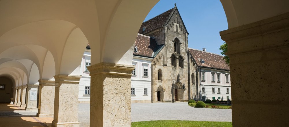 Blick von einem Säulengang auf den Eingang des Stifts Heiligenkreuz