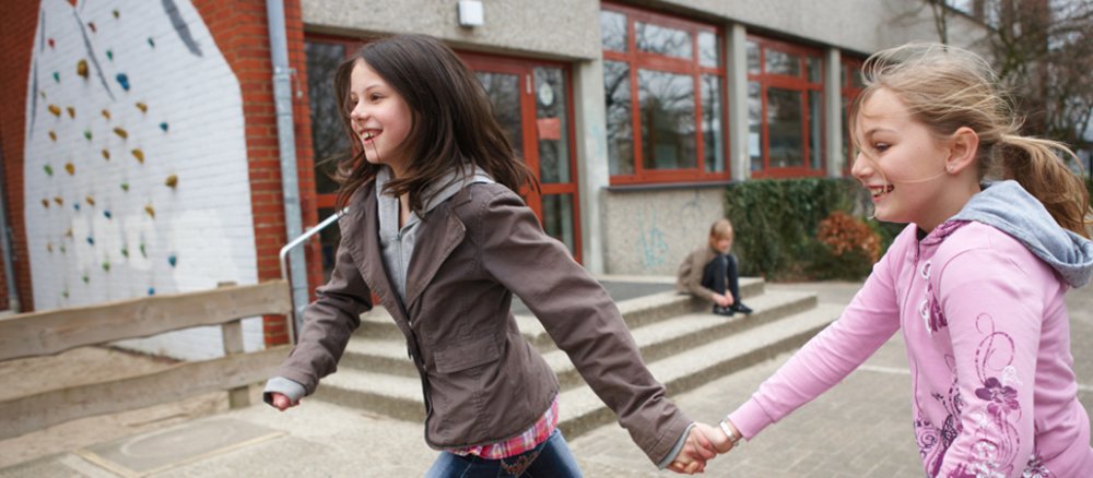 Zwei Mädchen rennen über den Schulhof