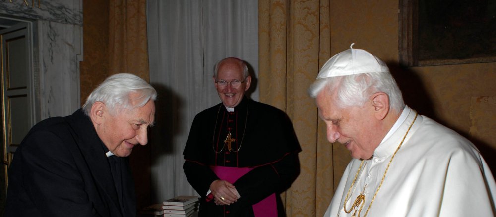 Georg Ratzinger (links) übergibt seinem Bruder Papst Benedikt XVI. (rechts) ein Buch.