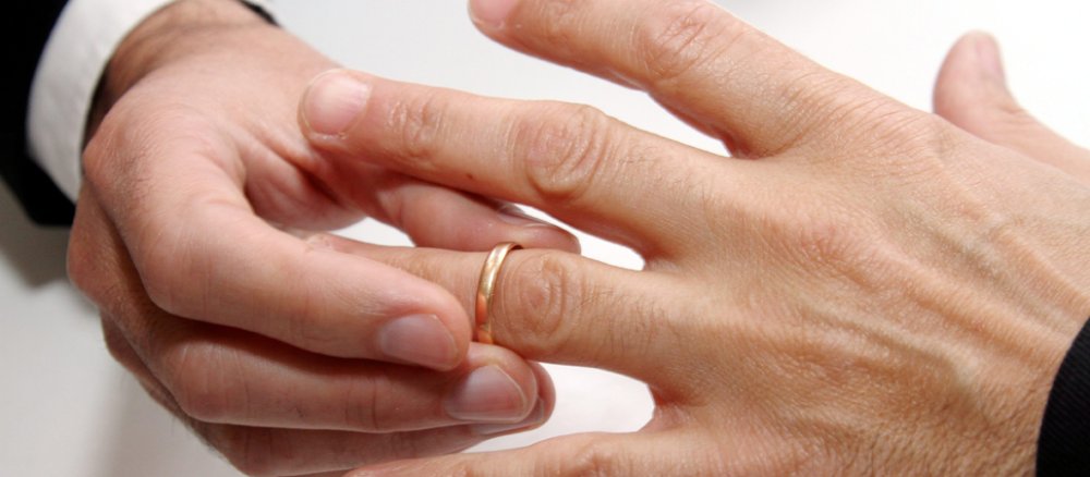Ein homosexuelles Paar steckt sich gegenseitig Eheringe bei der Eheschließung an.