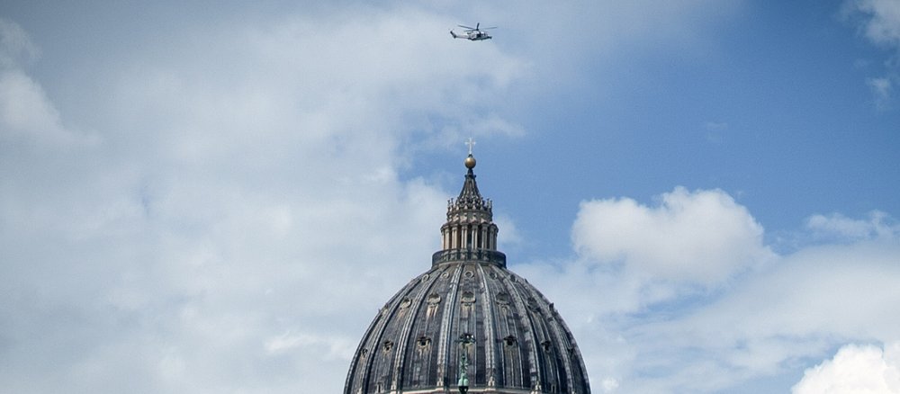 Ein Hubschrauber fliegt über die Kuppel des Petersdoms