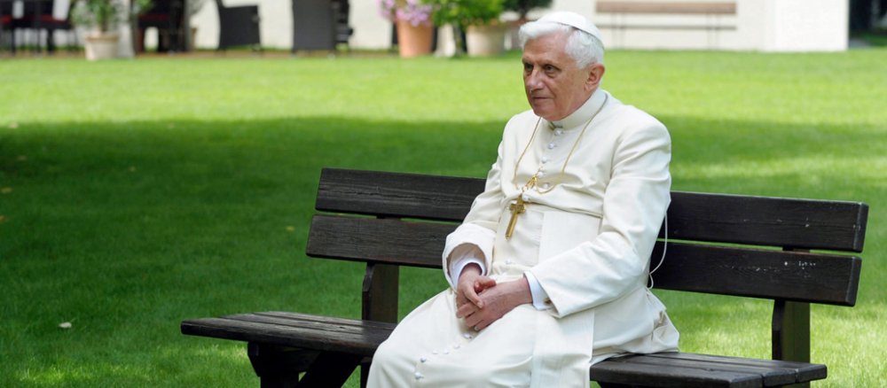 Benedikt XVI. sitzt auf einer Parkbank.