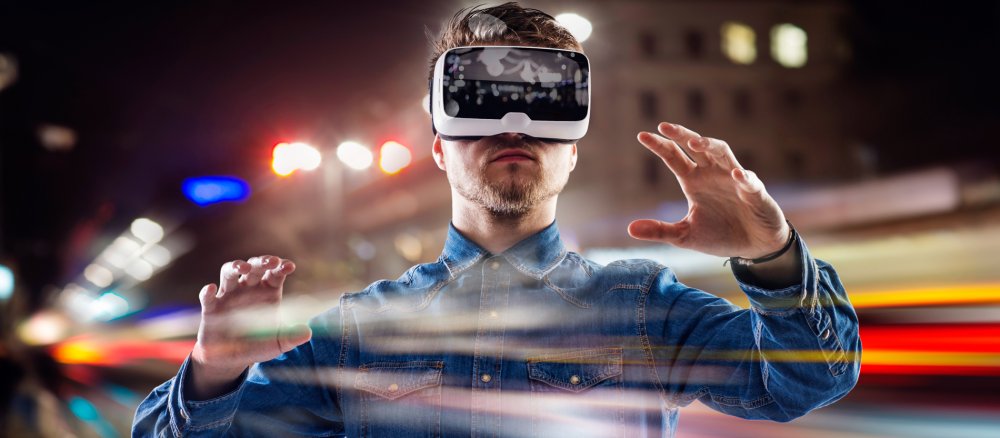 Ein Mann hat eine Brille auf, die eine virtuelle Realität vor seinen Augen entstehen lässt.