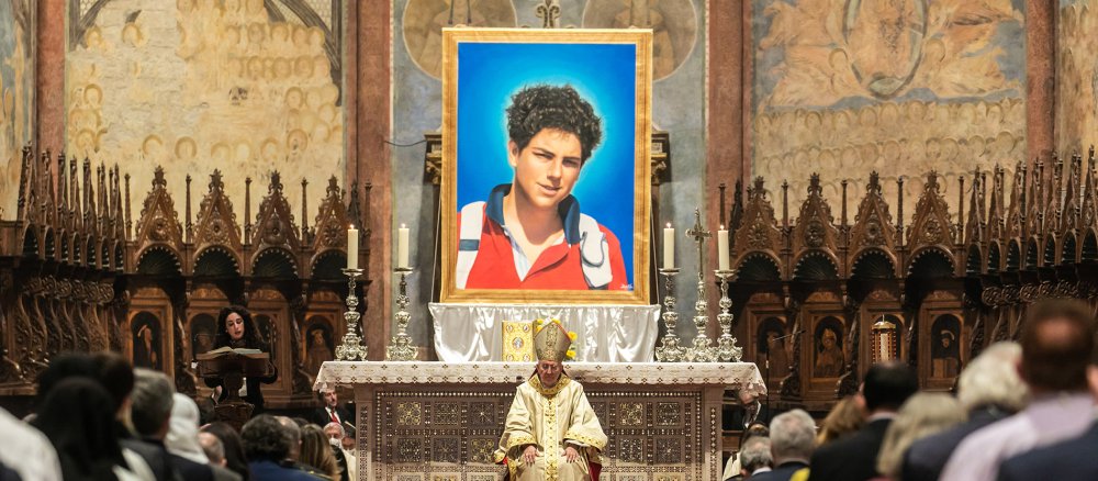 Seligsprechung von Carlo Acutis mit Agostino Vallini, emeritierter römischer Kardinalvikar, in der Basilika San Francesco in Assisi am 10. Oktober 2020. Hinter dem Altar hängt ein großes Bildnis des Seliggesprochenen.