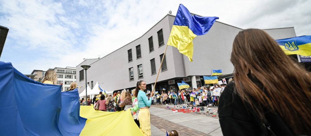 Demonstranten mit gelb-blauen Flaggen der Ukraine bei Protesten während des 102. Deutschen Katholikentags