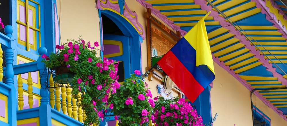 Eine kolumbianische Flagge weht auf dem farbenfrohen Balkon eines Hauses im Kolonialstil.