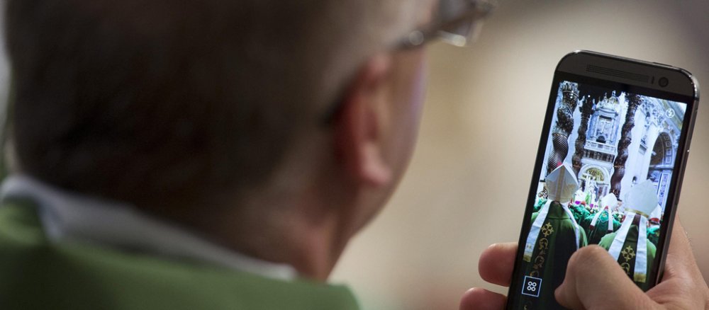 Während der Familiensynode im Vatikan nimmt ein Bischof ein Foto mit seinem Smartphone auf.