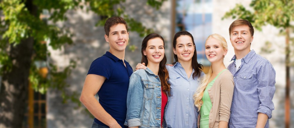 Drei jugne Frauen und zwei junge Männer lächeln in die Kamera. Wahrscheinlich sind es erfolgreiche Studenten.