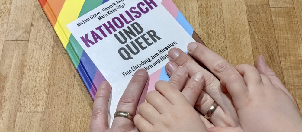 Hände liegen auf einem regenbogenfarbenen Buch