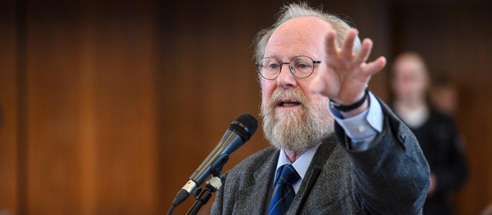 Wolfgang Thierse speaks into a microphone with his left hand gesturing towards the viewer.