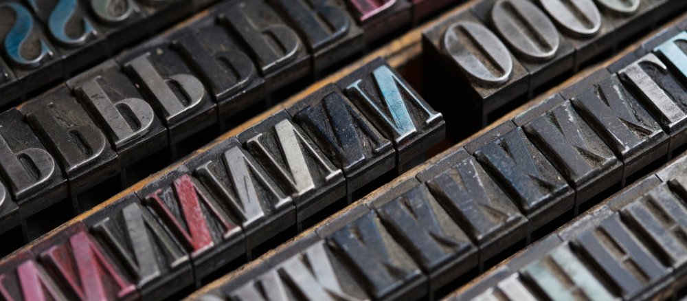Drucklettern eines "Times"-Schriftschnittes liegen in einem Setzkasten.