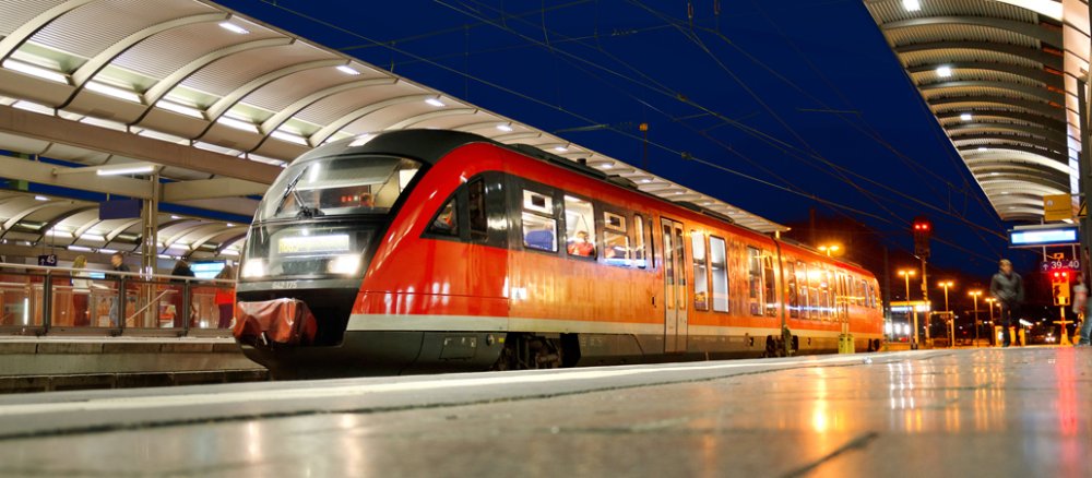 Beleuchteter Bahnsteig mit rotem Zug.