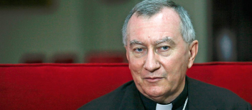 Parolin sitzt auf einem roten Sofa.