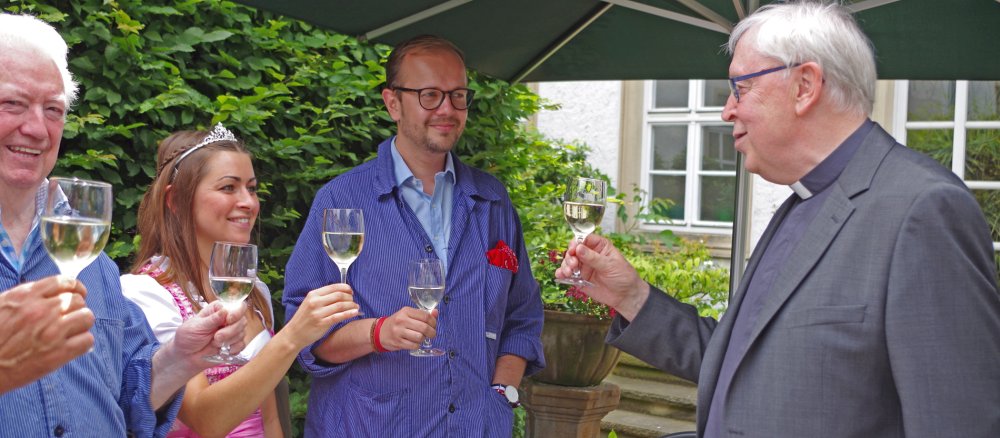 Bischof Trelle trinkt mit Gästen ein Glas Wein.