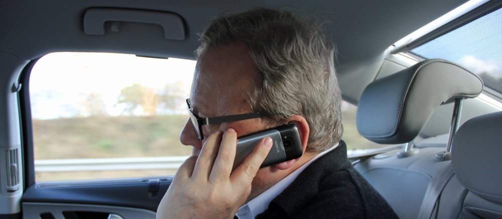 Bischof Bode sitzt im Auto mit dem Handy am Ohr