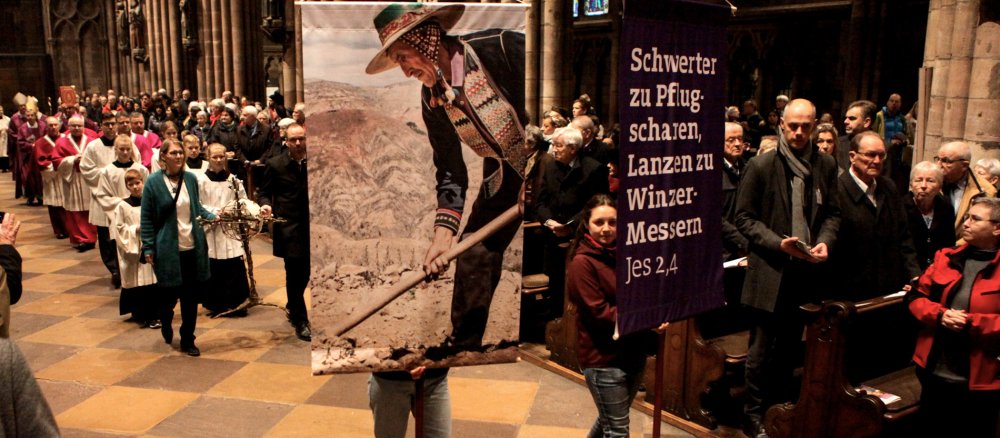 Jugendliche tragen Plakate mit Bildern aus Südamerika und Bibelzitaten beim Eröffnungsgottesdienst in Freiburg.
