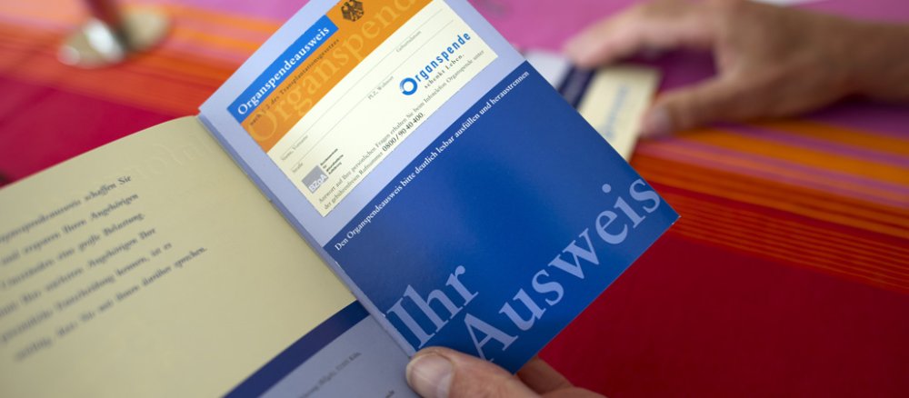 Eine Patientin hält eine Infobroschüre "Organspende schenkt Leben" in den Händen.