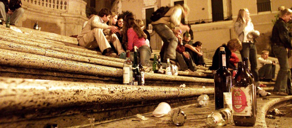 Junge Menschen sitzen auf der Spanischen Treppe in Rom und trinken Bier.