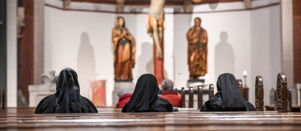 Drei Ordensfrauen sitzen in einer Kirchenbank