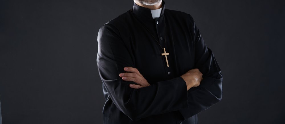 Ein Priester mit verschränkten Armen