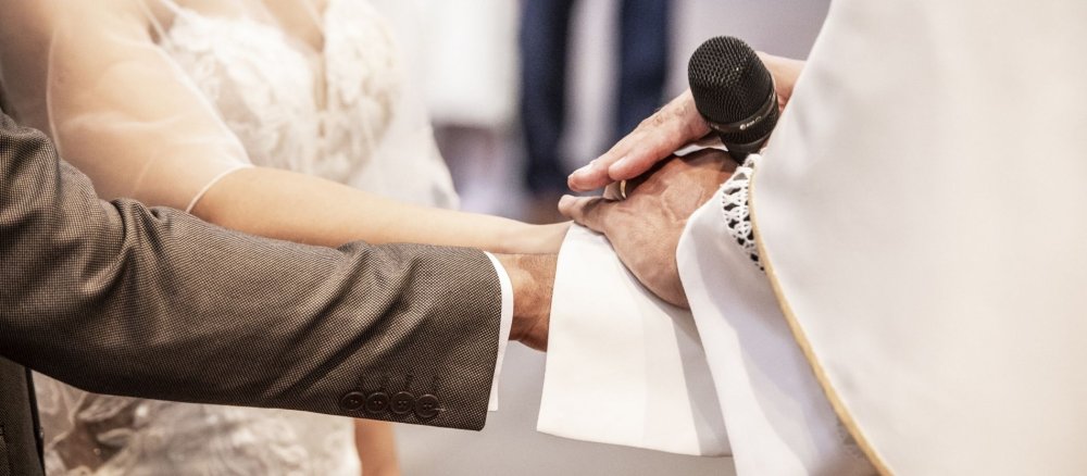 Ein Priester legt bei einem Hochzeitsgottesdienst die Stola um die Hände des Brautpaars
