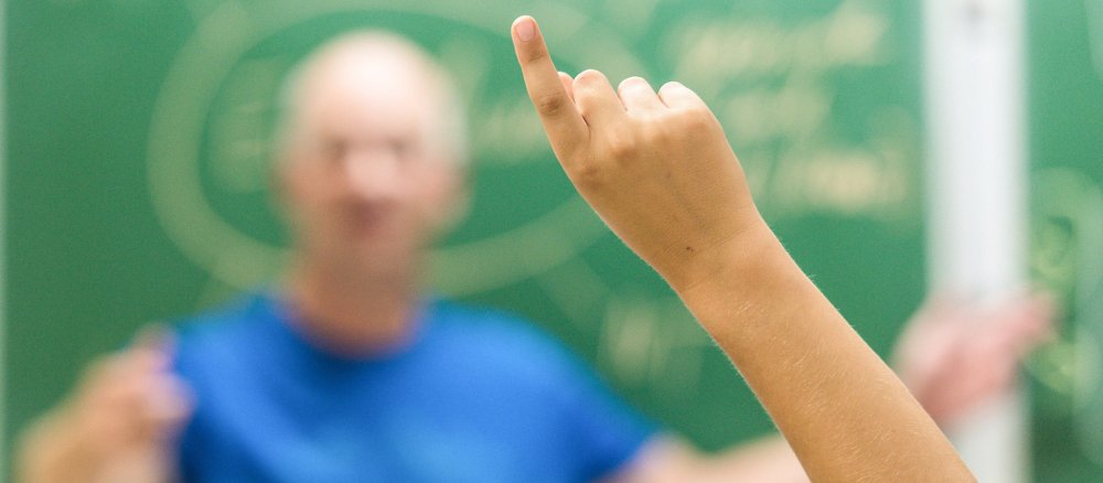 Ein Schüler zeigt im Klassenraum auf