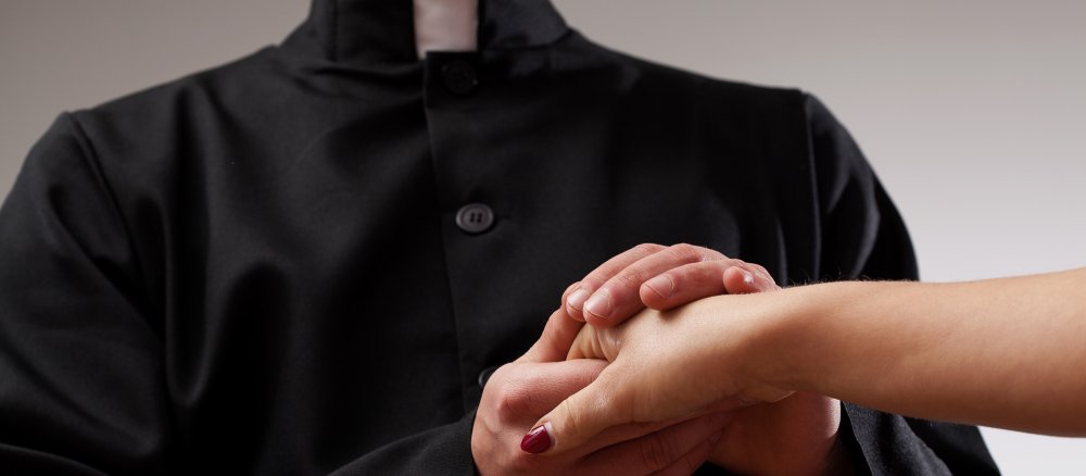 Priester hält Frauenhand
