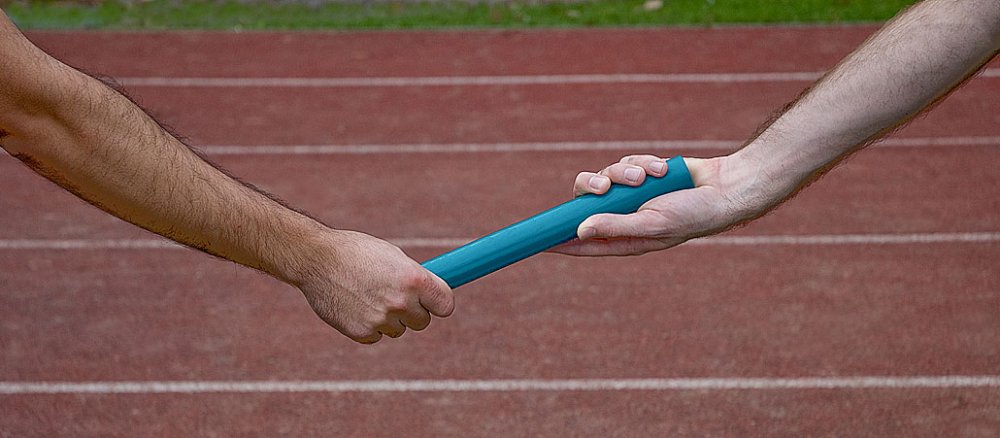 Übergabe eines Staffelholzes beim Stafelllauf.