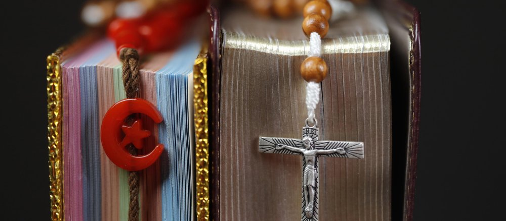 Religiöse Symbole für Christentum und Islam hängen vor zwei Büchern