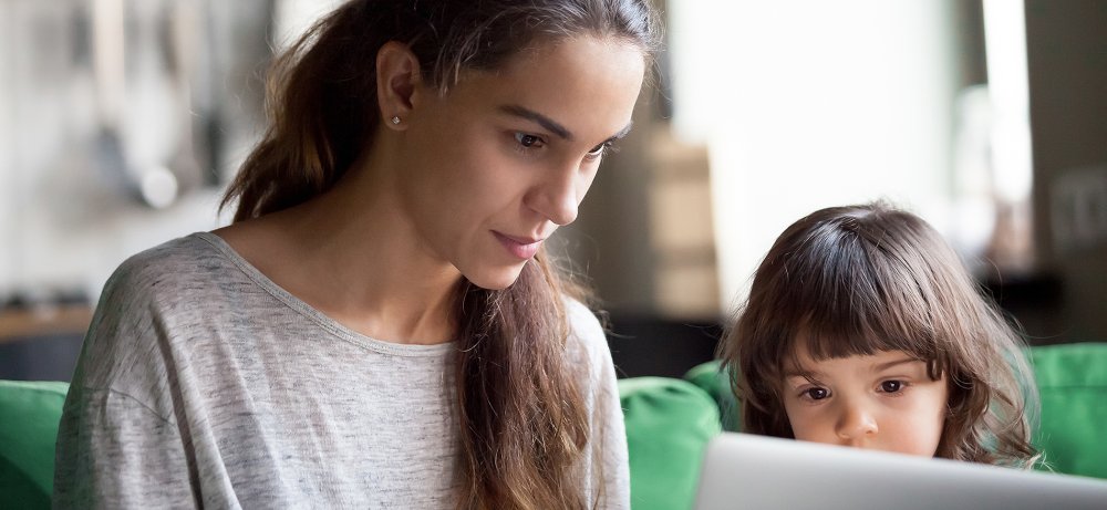Mutter, die Laptop zusammen mit kleiner Tochter verwendet