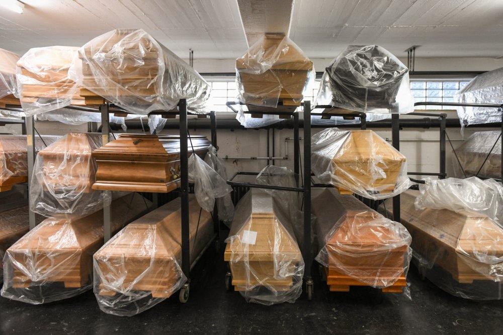 Särge stehen zum Teil in Folien eingepackt in einem Regal in einem Bestattungshaus