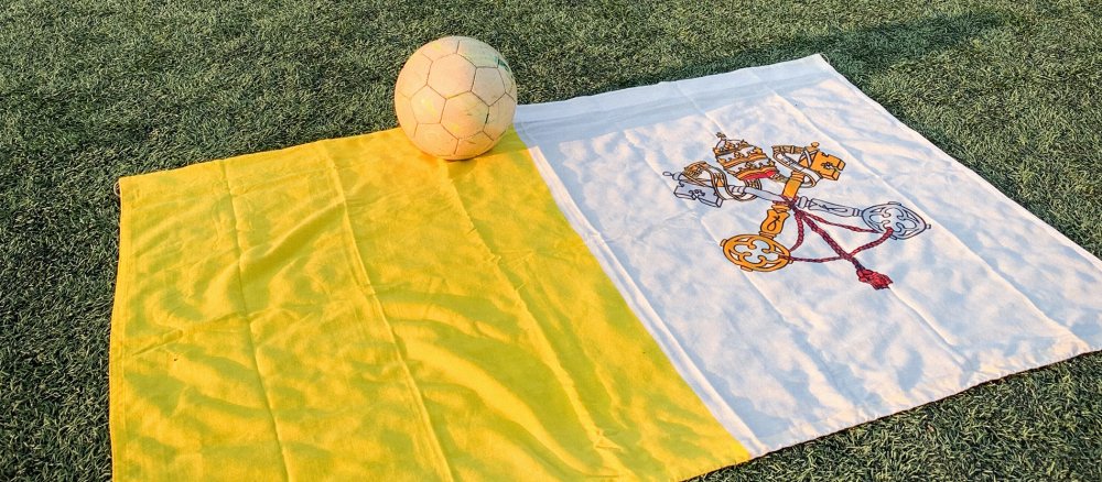 Die Vatikanflagge liegt mit einem Fußball auf dem Spielfeld