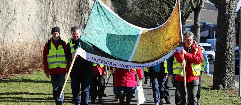 Menschen tragen das Hungertuch der Misereor-Fastenaktion