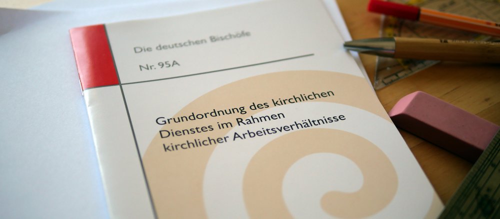 Ein Exemplar der Grundordnung des kirchlichen Dienstes liegt auf einem Schreibtisch.