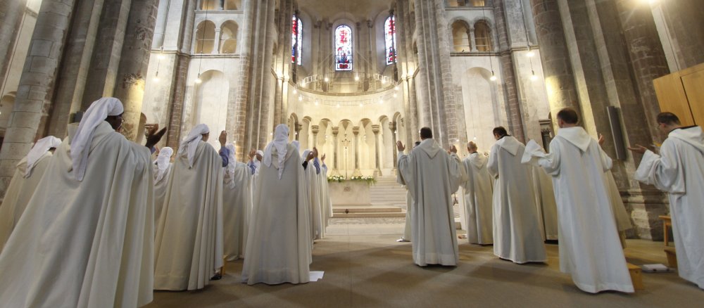 Männer und Frauen in Ordensgewändern stehen während des Stundengebets in der Kirche Groß Sankt Martin.