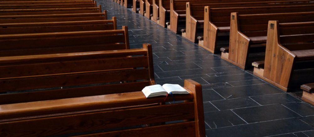Ein Gotteslob liegt in einer Kirchenbank.