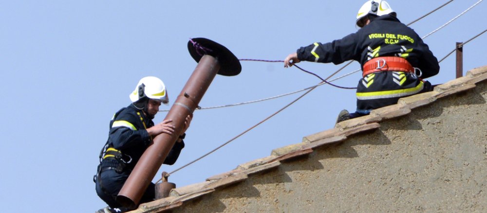 Arbeiter bringen den Schornstein auf dem Dach der Sixtinischen Kapelle an.