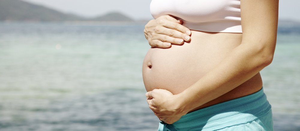 Eine Frau hält ihren schwangeren Bauch.
