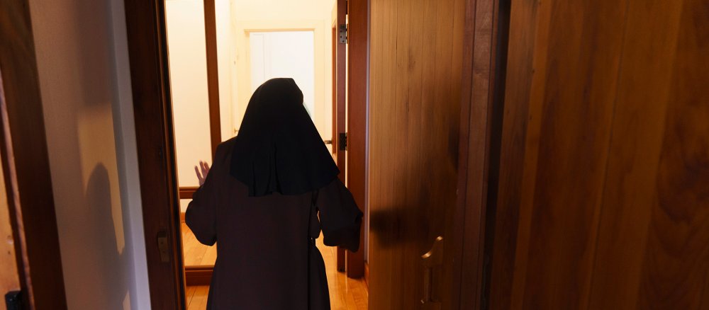 A Carmelite running towards a light-coloured corridor from behind