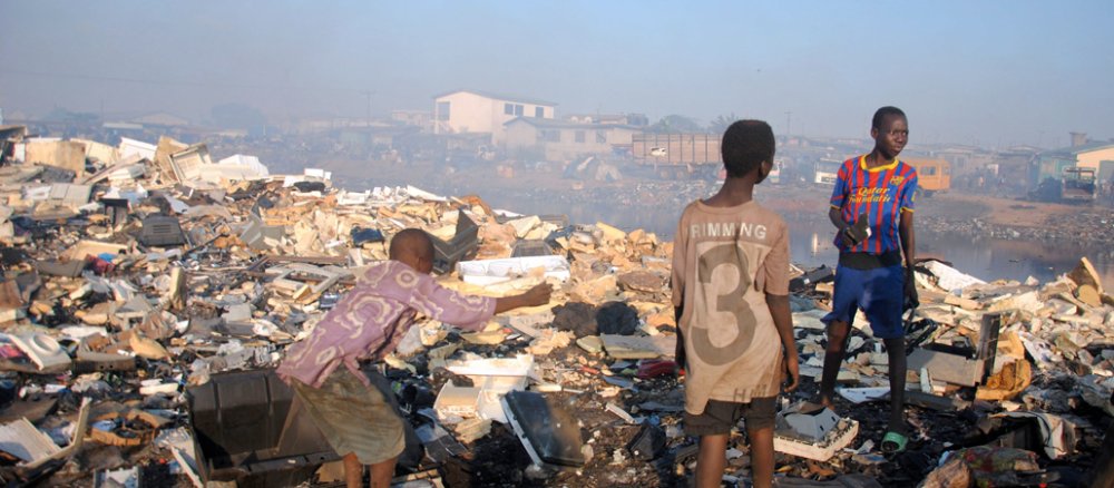 Drei afrikanische Jungen stehen auf einem Müllberg. Sie suchen auf der Elektroschrotthalde in Accra nach verwertbaren Materialien.