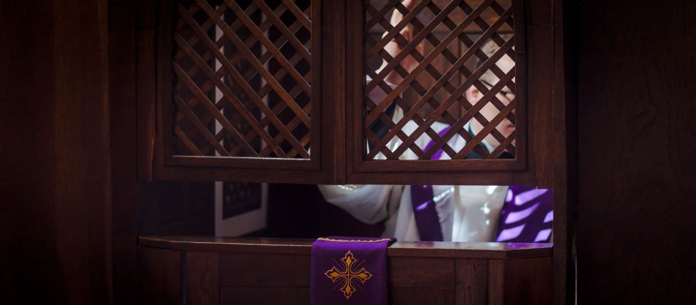 Ein Priester gewährt die Absolution im Beichtstuhl
