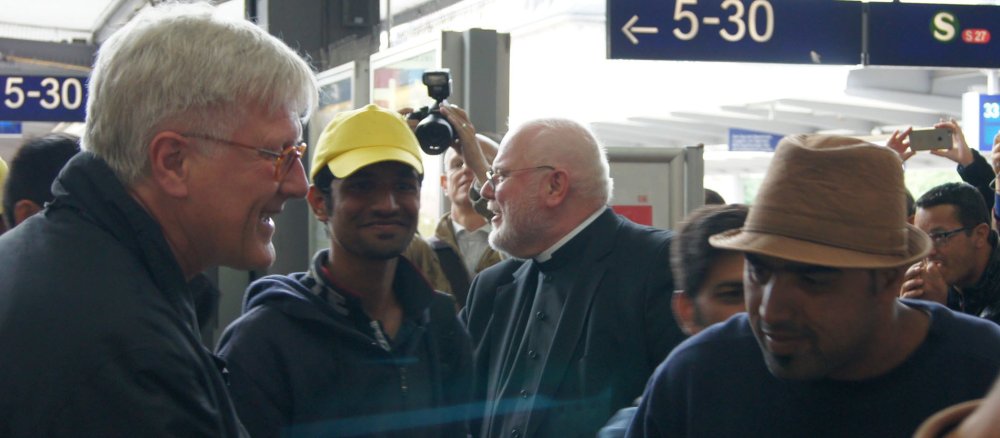 Heinrich Bedford-Strohm und Reinhard Marx schütteln Flüchtlingen die Hände