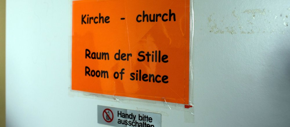 Eine Tür mit einem orangenen Schild mit der Aufschrift "Raum der Stille"