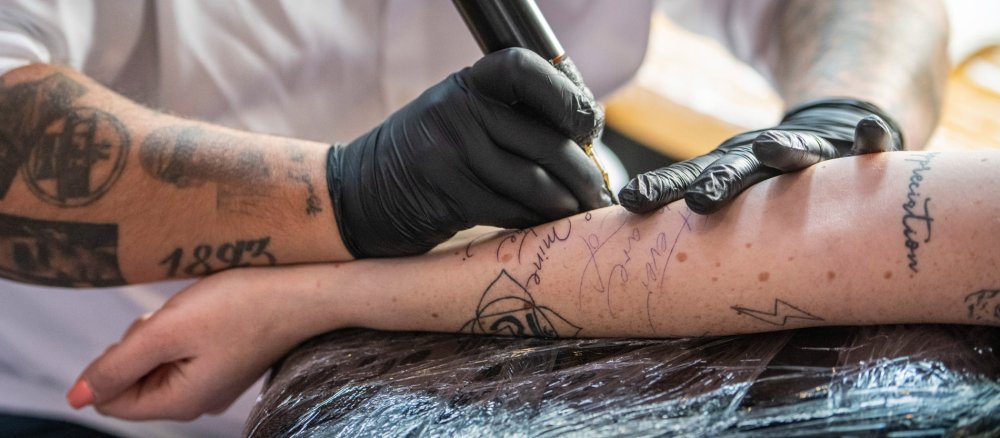 Eine Person wird am Arm tatowiert