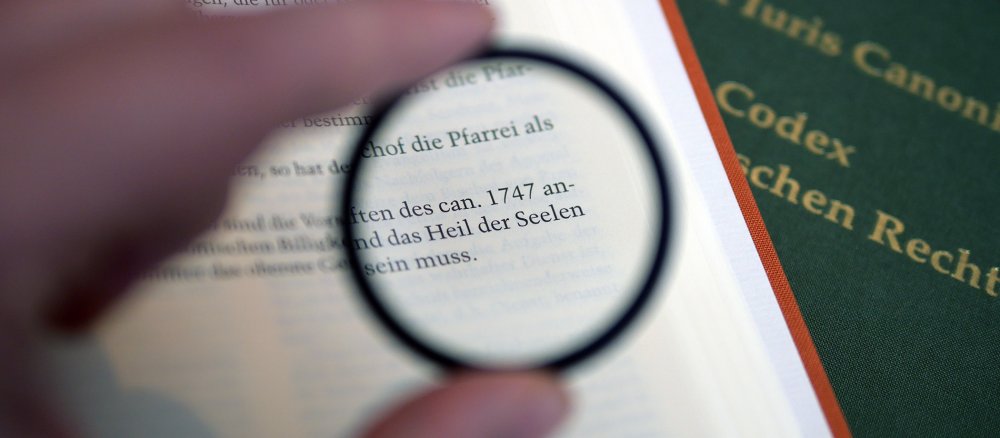 Eine Lupe wirft den Fokus auf den Ausdruck "Heil der Seelen" am Ende des kirchlichen Gesetzbuchs