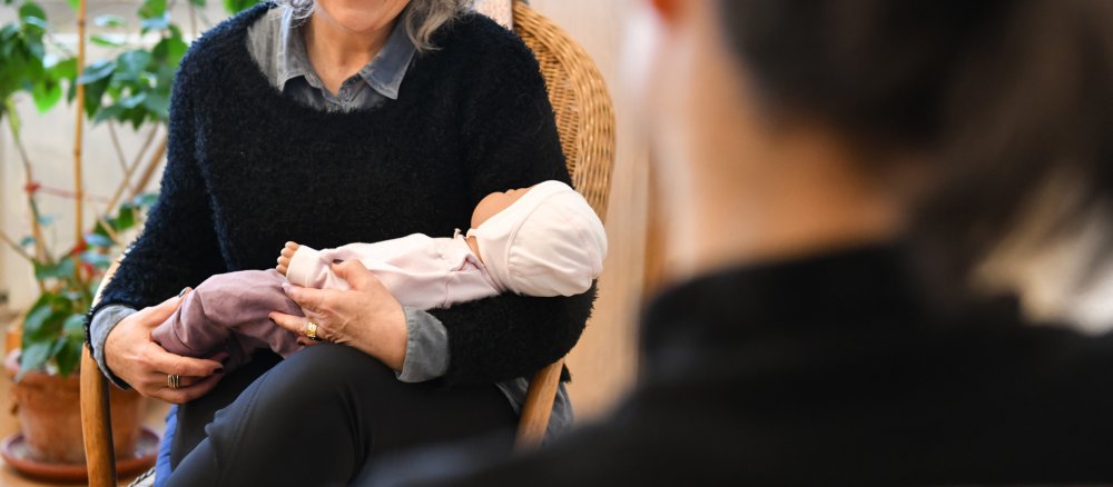 Eine Schwangerenkonfliktberatung. Die Sozialarbeiterin zeigt der Schwangeren eine Babypuppe.