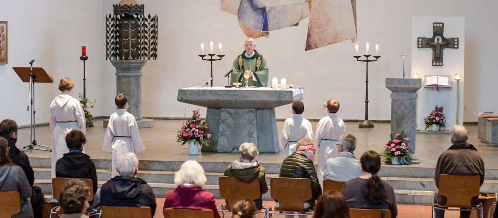 Ein Pfarrer hinter dem Altar davor die Gemeinde